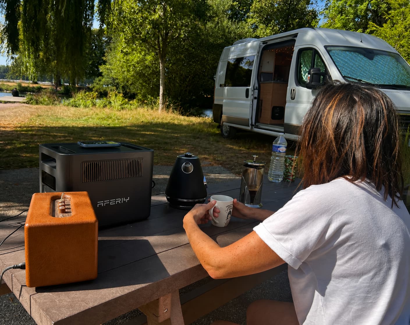 AFERIY Nomad1800 Pro alimentant une bouilloire et une enceinte sur une table de camping devant un van